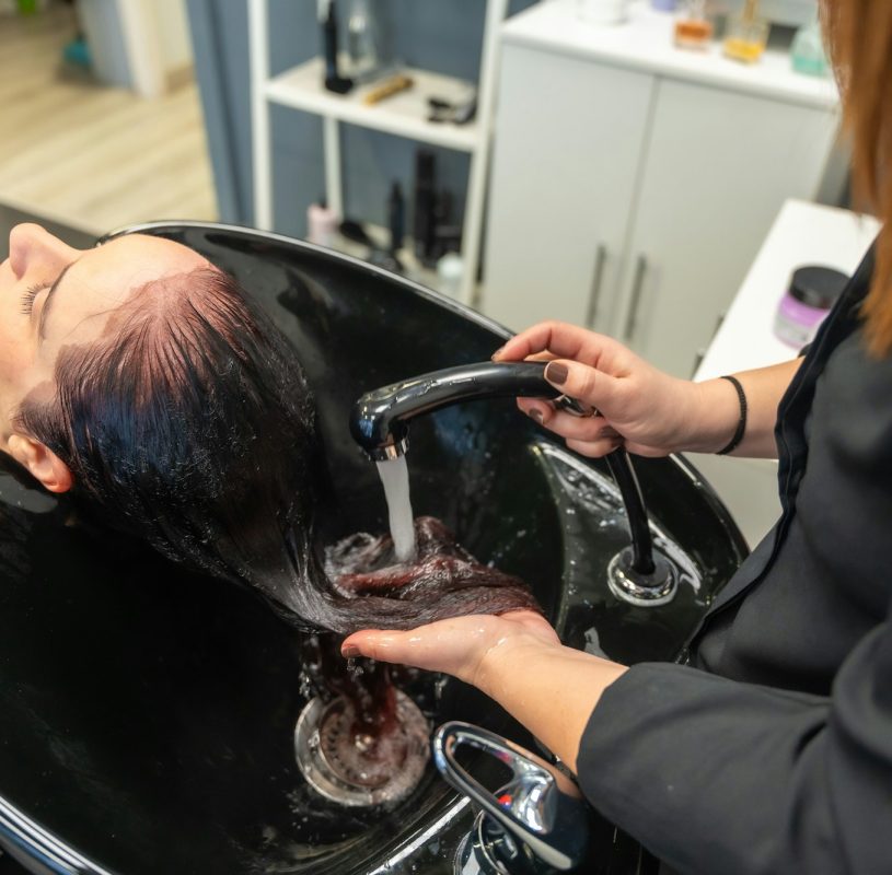 Hairdresser rinsing shampoo from a woman's hair at the salon