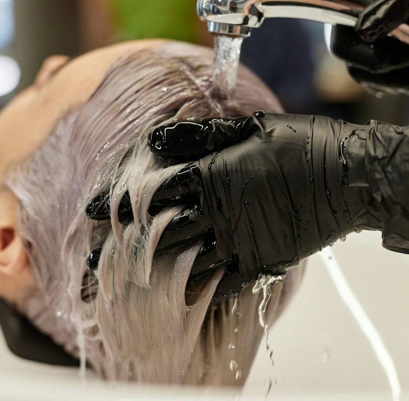 Hairstylist Washing Hair of Young Woman in Salon